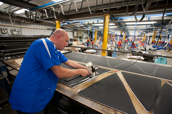 Man cutting out umbrella panels on workbench