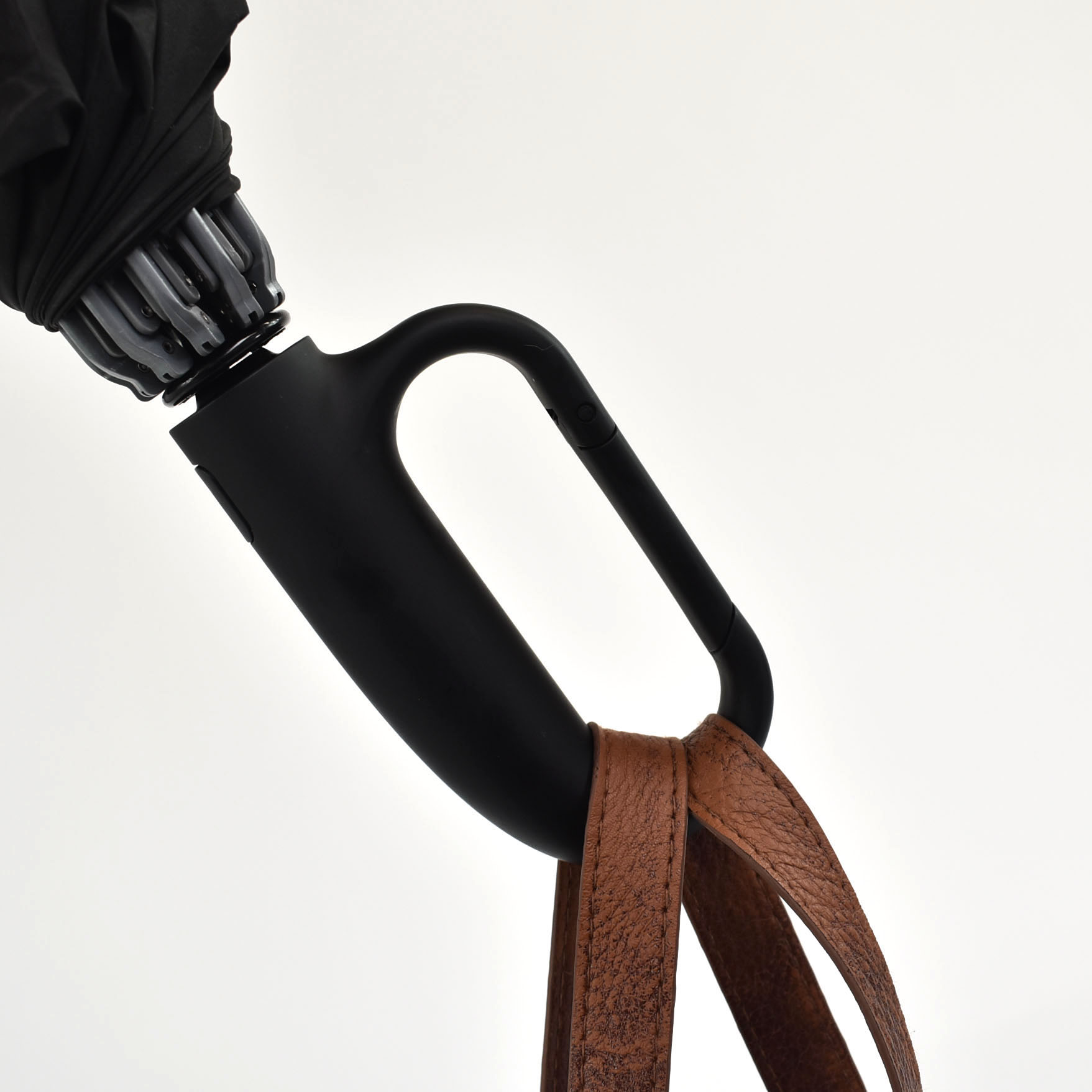 black clip handle on umbrella with brown bag strap attached