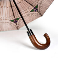 stained glass window printed on inside of umbrella with black pole of umbrella showing and polished dark wood handle
