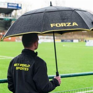 Man holding black and yellow umbrella loking onto a sports field
