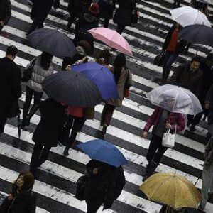 People walking accross cross walk with different coloured umbrellas