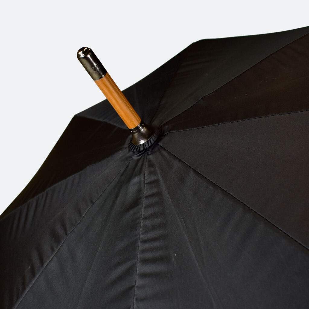 wooden tip of umbrella with metal tip and black panels of umbrella