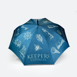 open Custom illustrated umbrella with blue panels and white print that says KEEPERS COTTAGES and outlines of bee, lighthouse, book, ice cream and crab